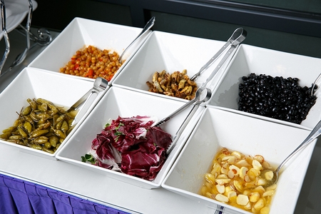 Various salad ingredients on china platter, in buffet background