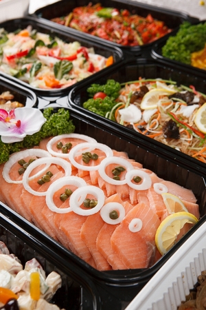 Salmon salad with sliced onions and caper, on black palstic plateの写真素材