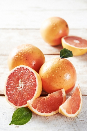 sliced and whole grapefruits on tableの写真素材
