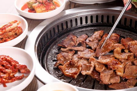 Chopsticks grabbing marinated pork spareribs being grilled on grillの写真素材