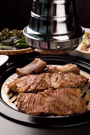 Marinated pork spareribs being grilled on stainless grillの写真素材