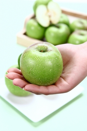 green apple with drops on a handの写真素材