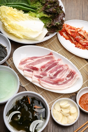 Raw pork belly on round plate with side dishesの写真素材