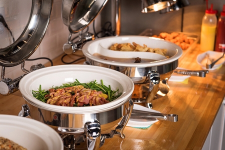 Chives and smoked duck on large china plate, buffet background