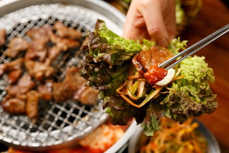 Marinated pork spareribs being grilled on grill, wrapped in vegetablesの写真素材