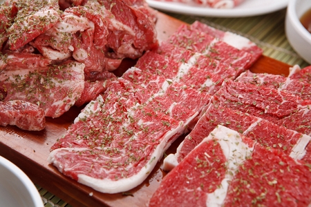 raw beef sprinkled with parsley, on wooden cutting boardの写真素材