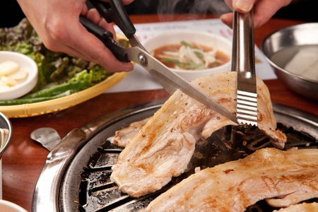 scissors and pincers cutting pork bellyの写真素材