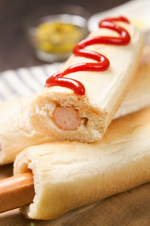 hotdog with ketchup on wooden plateの写真素材