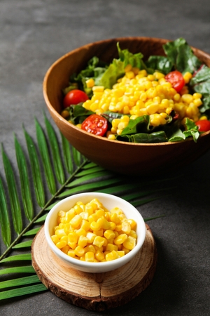 corn salad made of tomatoes, vegetables and corn on round plate, and corn on small plateの写真素材