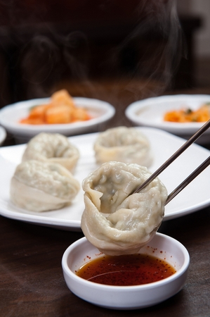 chopsticks grabbing steamed dumplings dipped in soy sauceの写真素材