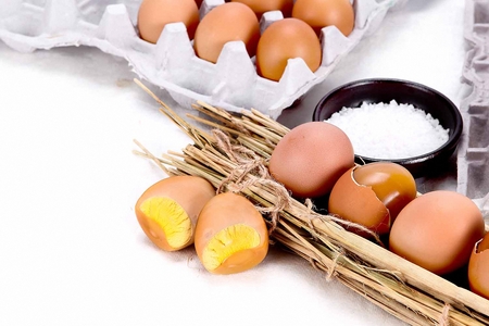 roasted eggs on straw, with a small plate with salt, in white background