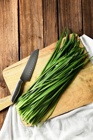 chives and knife on wooden cutting boardの写真素材