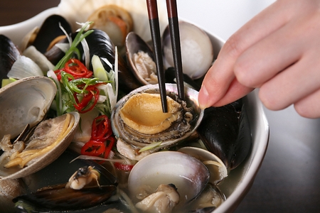 chopsticks grabbing abalones from seafood ramyunの写真素材