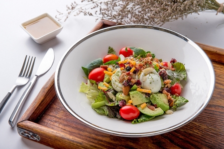 salad with cherry tomatoes, eggs, almonds, cheese, avocado and vegetablesの写真素材