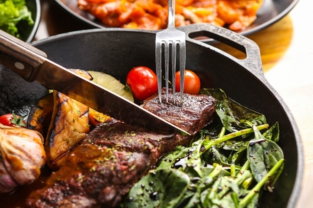 fork and knife cutting steak on plateの写真素材