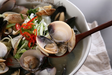 spoon scooping up seashells from seafood ramyunの写真素材