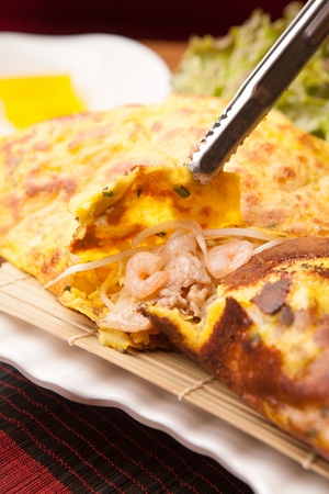 banh xeo split apart with pincers, showing its stuffingsの写真素材