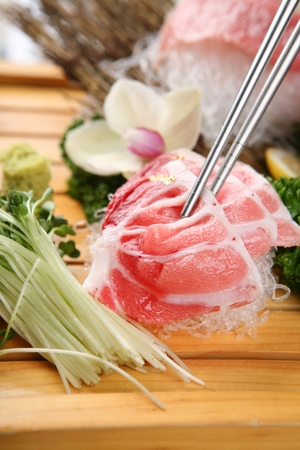 chopsticks grabbing raw tuna and sprouts on wooden plateの写真素材
