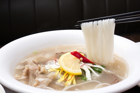 chopsticks grabbing rice noodles with meatの写真素材