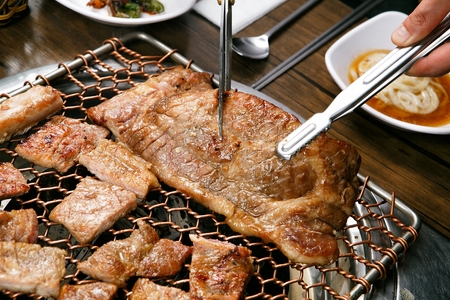 tongs and scissors cutting marinated spareribsの写真素材