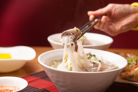 chopsticks grabbing rice noodles with meatの写真素材