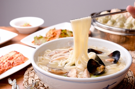 chopsticks grabbing chopped noodles soup with various seafoodの写真素材