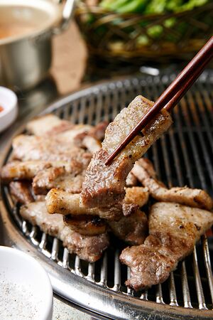 Grilled pork belly grabbed with chopsticksの写真素材