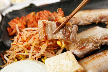 Grilled pork belly grabbed with chopsticksの写真素材