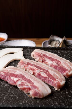 Pork belly being grilled with mushrooms on grillの写真素材