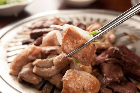 Chopsticks grabbing grilled entrails cooked on grillの写真素材