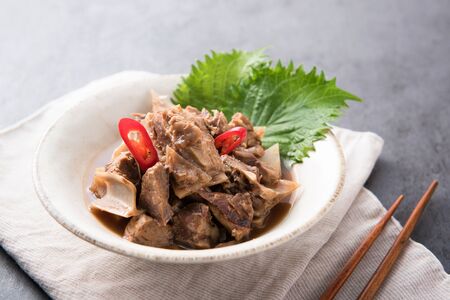 Marinated beef cubes with chili slices on top served on white round plateの写真素材