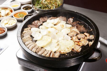 Entrails, potatoes, and onions being grilled on grillの写真素材