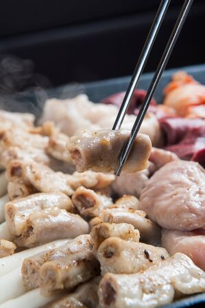Chopsticks grabbing grilled entrail assortment cooked on grillの写真素材