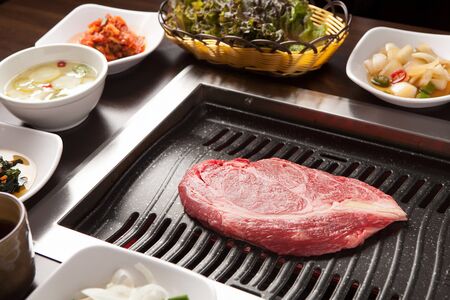 a chunk of sirloin on grill with side dishesの写真素材