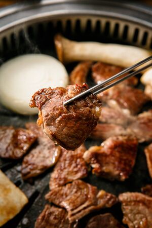chopsticks grabbing a slice of meat with mushrooms and onionsの写真素材