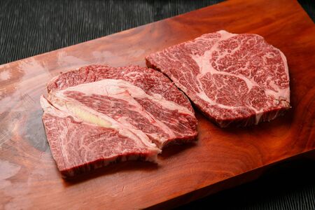 raw chunks of sirloin on rectangular wooden cutting boardの写真素材