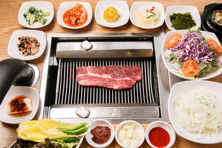 sirloin on grill with various side dishes, vegetables, garlic and sauceの写真素材