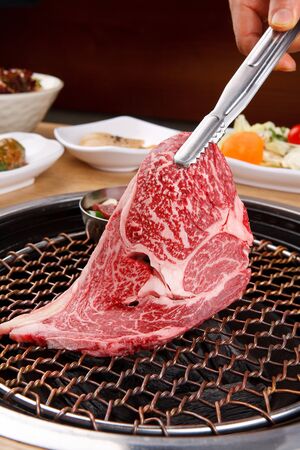 raw sirloin on grill with side dishesの写真素材