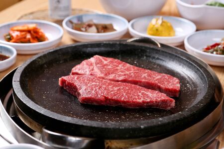 raw sirloin on grill with side dishesの写真素材