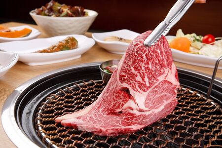 raw sirloin on grill with side dishesの写真素材