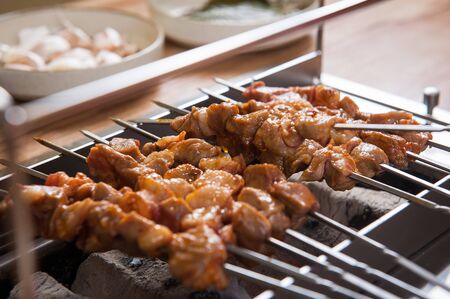 lamb skewers being grilled on charcoalの写真素材