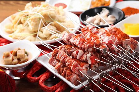 raw lamb skewers with red sauce and side dishesの写真素材