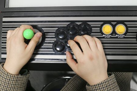 Hand on arcade game control panel and joystick