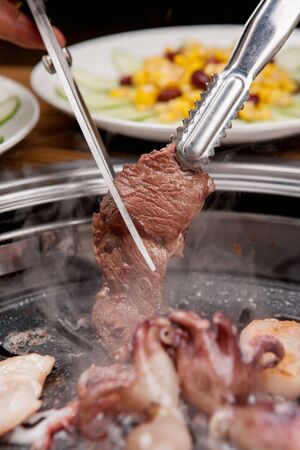assorted grilled meat on grill, being cut with scissors and pincersの写真素材