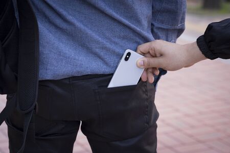 Criminal concept photo, Male Thief is stealing mobile phone from a man pocket at street