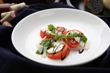 caprese salad with sliced tomato and cheese with dressingの写真素材