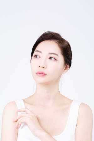 beautiful Asian woman with white sleeveless, white background shot with beauty cosmetics conceptの写真素材