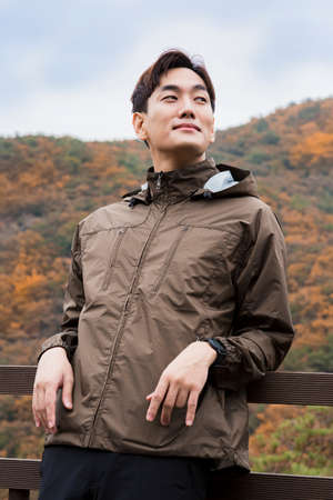 Asian handsome man trekking, climbing autumn mountain