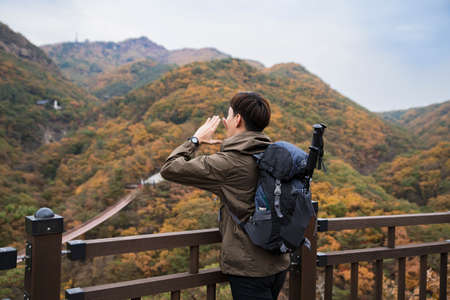 Asian handsome man trekking, climbing autumn mountainの写真素材