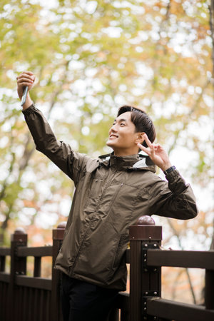 Asian handsome man trekking, climbing autumn mountainの写真素材